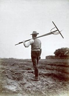 Images Dated 22nd March 2007: Peasant seen from the back as he walks along with a rake and a pitchfork on his shoulder