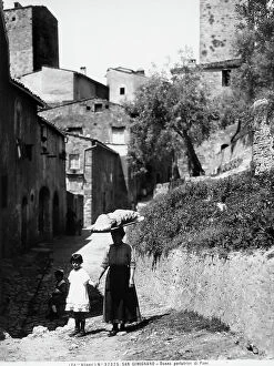 Images Dated 20th March 2009: Portrait of a woman carrying bread with child, San Gimignano is in the background