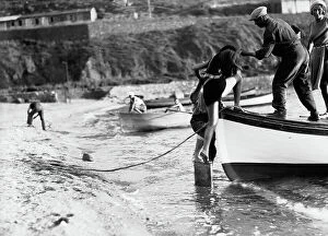 Images Dated 6th May 2009: Woman being helped to get on a boat by the sea