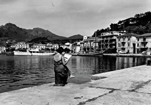 Images Dated 16th July 2009: A woman reads a newspaper on the quay of the port of Porto Azzurro on Elba Island