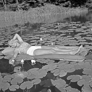 Freizeit Print: Young Woman on Air Mattress with Water Lilies
