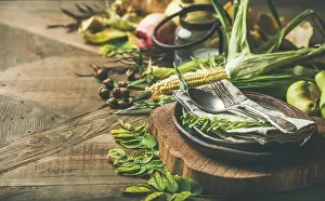 Prints of Fall table setting for Thanksgiving celebration. Flat-lay of plate, cutlery, candle holder, Autumn seasonal vegetables, fruit and fallen leaves for decor over wooden background, copy space August Prints: Fall Table Setting Print