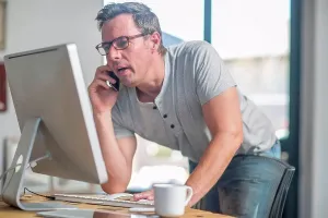 Man Using Smartphone Prints: Man at computer using smartphone to make telephone call