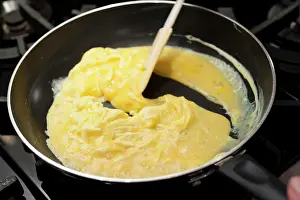 Prints of Preparing scrambled eggs in a pan May Prints: Scrambled eggs pan print