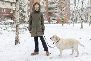 Winter Portrait Prints: Affection Moment. Outdoor winter scene where woman shares tender moment with pet dog surrounded by snow and bare trees