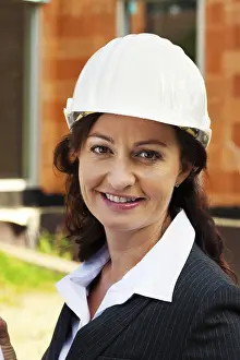 Residential Building Design Prints: Architect with building plan in front of the shell of a house during construction