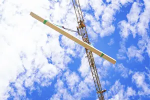 Empty Construction Site Prints: A beam is hoisted by a crane, sky and clouds in the background