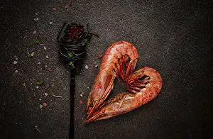 Prints of Black spaghetti, wrapped on a fork, langoustines in the shape of a heart, on the table, dish concept, dish background, top view Langoustine Prints: Black Spaghetti Print - Romantic Seafood Dish