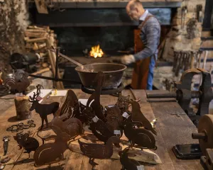 Rustic Wooden Table Scene Prints: A blacksmith works near a forge in a rustic workshop
