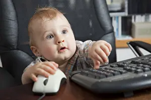 Young Boy At Desk Prints: Boy, 10 months, using a computer mouse and keyboard