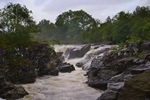 Cloudy Sky Over Water Prints: A bubbling river flows through a tree-lined