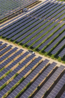 Agri PV Germany Prints: A car on a path between vast fields of solar panels