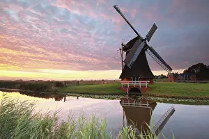 Benelux Countryside View Prints: Charming windmill by river at dramatic sunrise