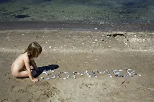 Waterfront Recreation Prints: Child playing with shells on the beach