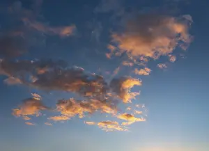 Cloudy Skies Background Prints: Clouds glow orange in the evening light