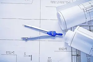 Construction Plan Prints: Compass and two rolled up white blueprints horizontal version