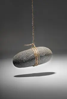 Elevated Studio Shot Prints: Conceptual image of a small rock hanging on a string