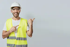 Young Adult Man Prints: Construction engineer with vest pointing at an advertisement