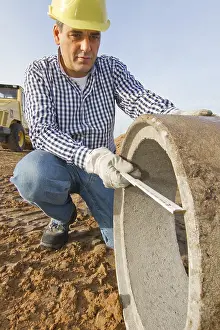 German Construction Site Prints: A construction worker checks a sewage pipe