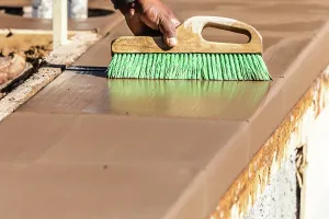 Building A Deck Prints: Construction Worker Using Brush On Wet Cement Forming Coping Around New Pool