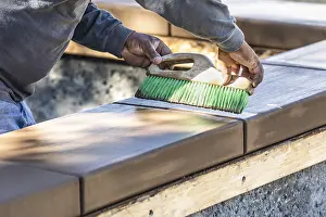 Masonry Work Prints: Construction worker using brush on wet cement forming coping around new pool