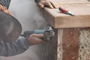 Male Construction Worker Prints: Construction worker using grinder at construction site