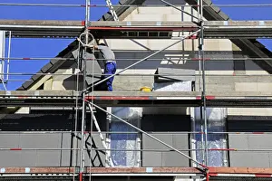 Energy Saving Construction Prints: Construction workers insulate a house facade
