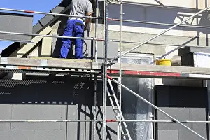 Construction Site Laborer Prints: Construction workers insulate a house facade