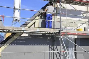 Construction Site Workman Prints: Construction workers insulate a house facade