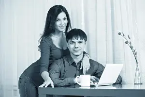 Married Couple Using Laptop Prints: Couple having coffee while using a laptop in their kitchen