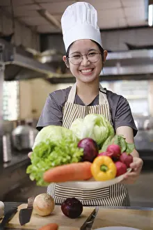 Fresh Ingredients Photography Prints: A culinary student stands in a professional training kitchen