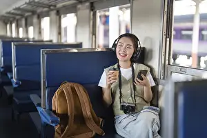 Young Woman On Train Prints: With a cup of coffee in one hand