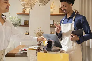 Contemporary Interior Design Prints: A customer makes a payment using a card at a chic bag store