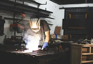 Factory Interior Photography Prints: Deaf man using a welding torch in the workshop