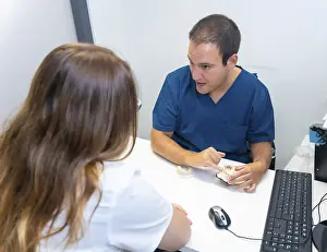 Healthcare Professional Consultation Prints: Dental clinic, dentist explaining to a client the teeth to be implanted in a model