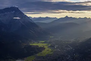 Bavarian Alps Prints: Distant view of town in front of mountains in the evening light