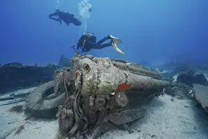 Russian Hydrofoil Wreck Dive Site Prints: Two divers explore the engine of a large wreck on the seabed