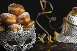 Deserted Carnival Scene Prints: Doughnuts against a dark background next to a silver hat