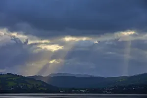 Northern Europe Waterfront Scene Prints: Dramatic rays of light through a cloudy landscape over a lake