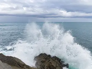 Panoramic Ocean View Prints: A dramatic scene as powerful waves collide with rugged rocks under a brooding sky
