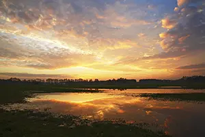Idyllic German Countryside Prints: Dramatic sky at sunset with reflection in flooded meadow