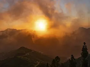Cloudy Evening Sky Photography Prints: Dramatic sunset lighting up the clouds and mist over the mountains