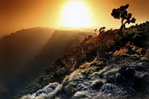 Atmospheric Landscapes Prints: Dramatic sunset over a mountain landscape with tree