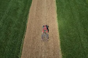 Agricultural Landscape In Austria Prints: Drone view, tractor at work between green fields