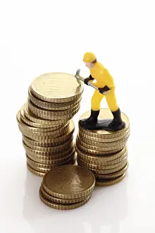 Euro Coin Stack Prints: Figure of a construction worker with hard hat and pickaxe on a stack of coins