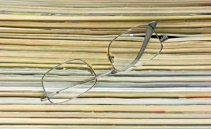 Magazine Stack Prints: Glasses on the background of the stack of magazines
