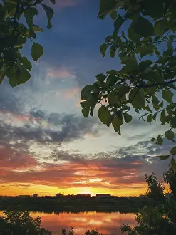 Prints of Gorgeous summer sunset as seen from the garden among the green trees. Sundown view over the city horizon reflected on the calm Delia lake water in Ungheni city, Moldova Moldova Prints: Gorgeous Summer Sunset Print, Ungheni City, Moldova