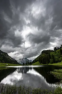 Empty Countryside Landscapes Prints: Groppelensee with reflection of the Altmann summit in the background under a threatening cloudy sky
