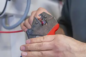 Electrician At Work Prints: Hand holding pliers that process a cable