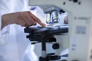 Working Clothes Europe Prints: Hand of a lab technician with microscope and sample working in a lab with light microscope